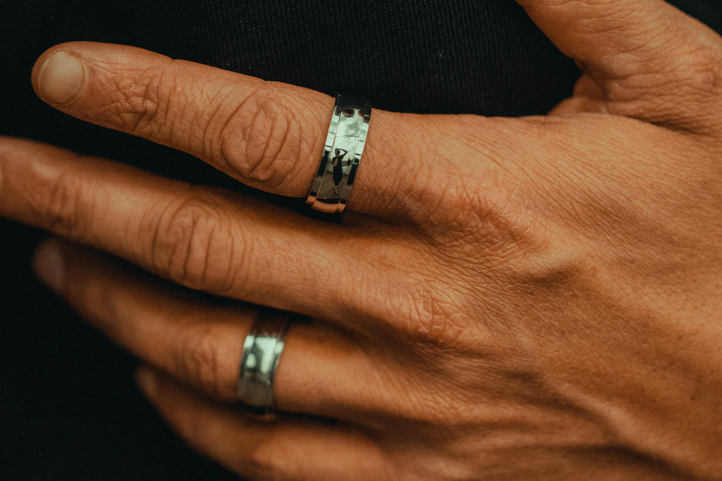 a man's hand in two silver rings.
