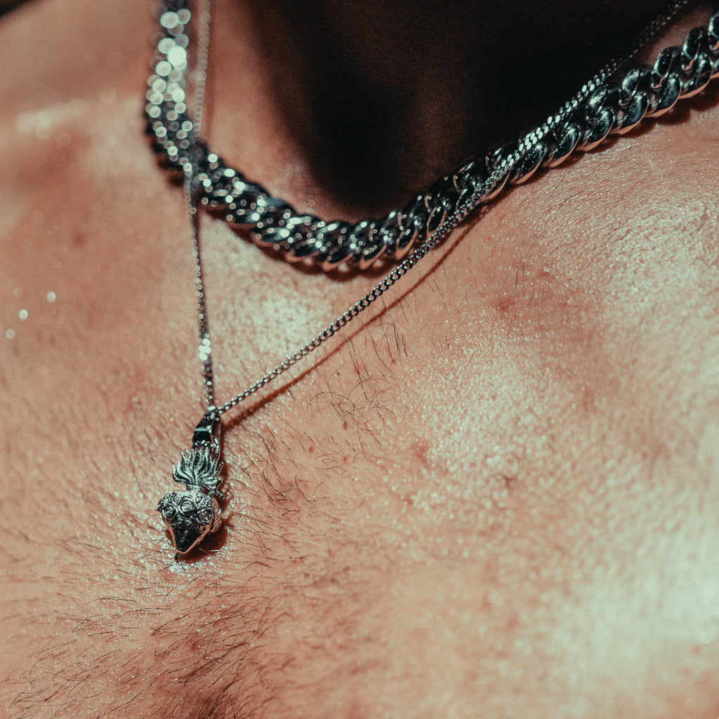 Heart pendant worn by a man with a cuban chain on.